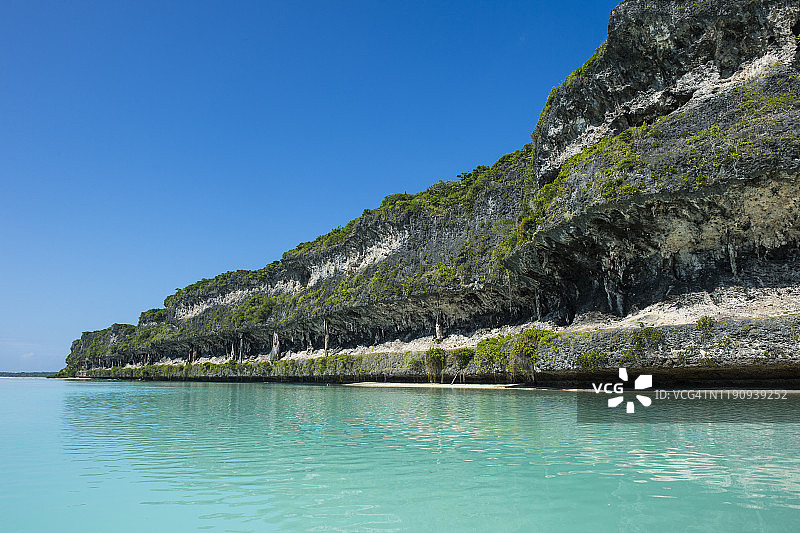 新喀里多尼亚乌韦阿拉耶蒂群岛碧海蓝天下灰色的勒金尼悬崖图片素材