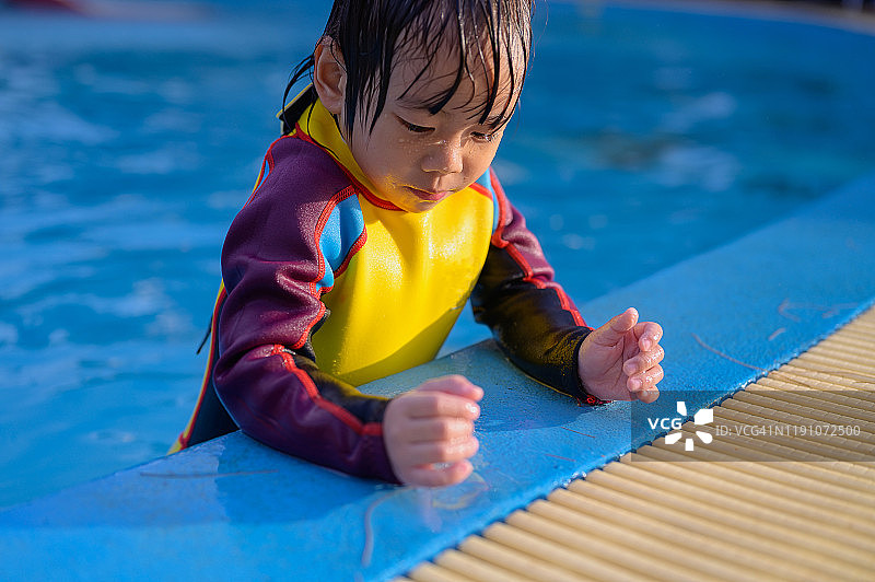 亚洲小孩在一个水上公园游泳池里玩得很开心。被一桶冷水泼后，又笑又叫图片素材