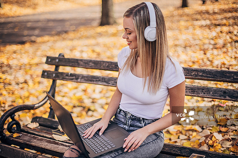 美丽的年轻女子正在公园里使用笔记本电脑图片素材