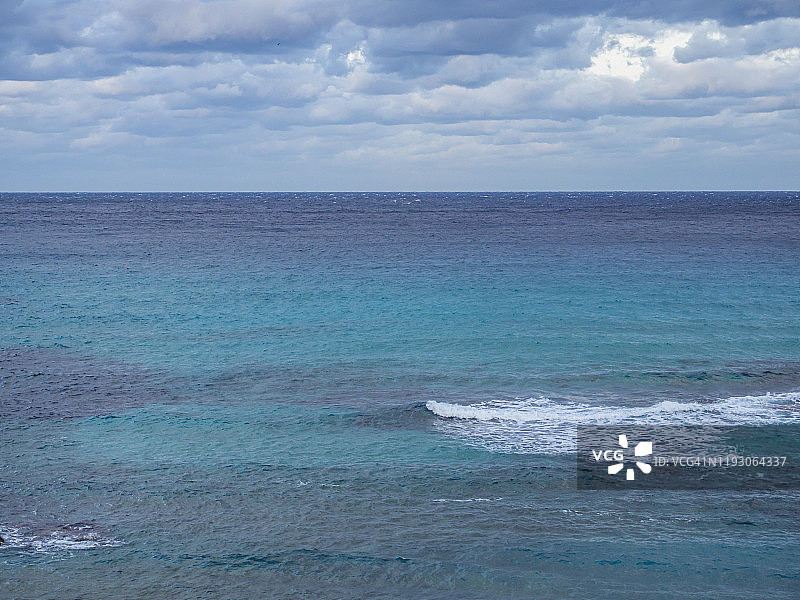 黄昏海景与戏剧性的天空与暴风雨的云和蓝绿色的海水图片素材