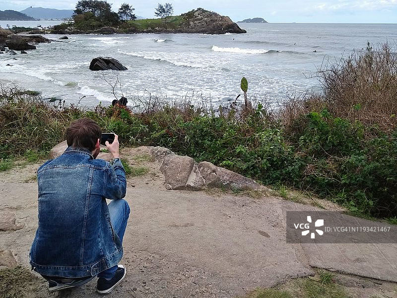 巴西圣卡塔琳娜，弗洛里亚诺波利斯，一名男子正在拍摄马塔迪罗海滩上的海洋图片素材