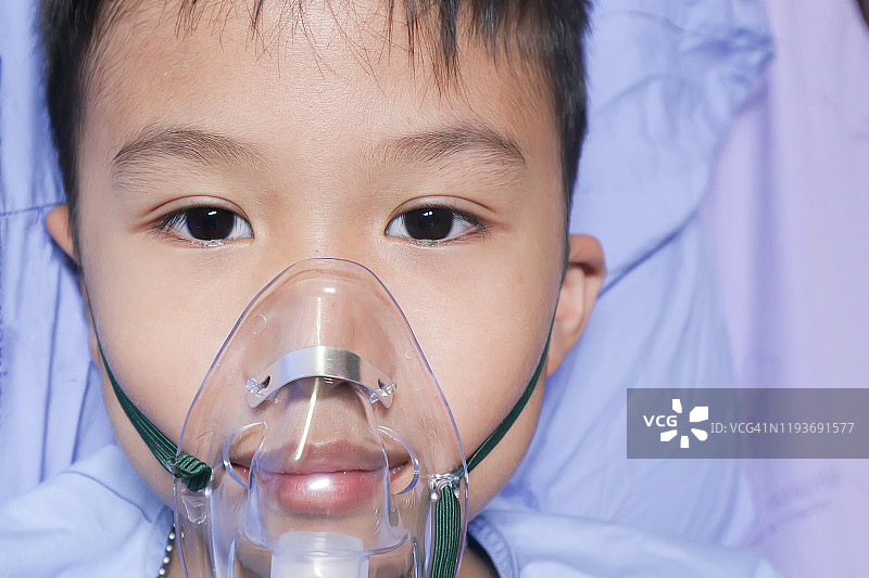 男孩哮喘过敏患者使用哮喘吸入器。在医院治疗的吸入器面罩。健康哮喘住院医疗保健理念图片素材