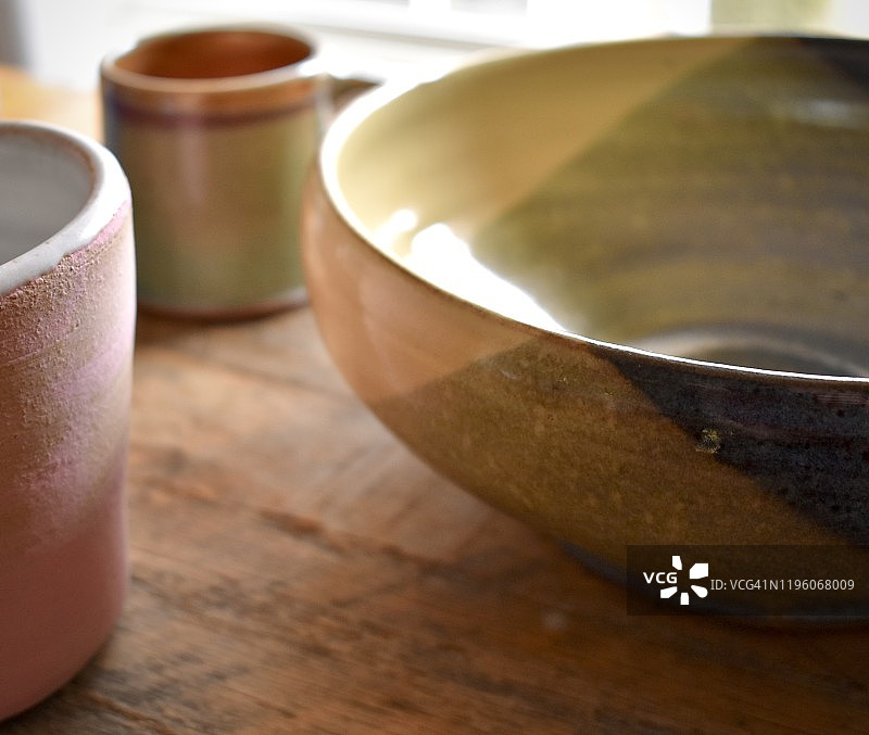 在明亮的阳光下手工制作的陶杯和陶碗图片素材