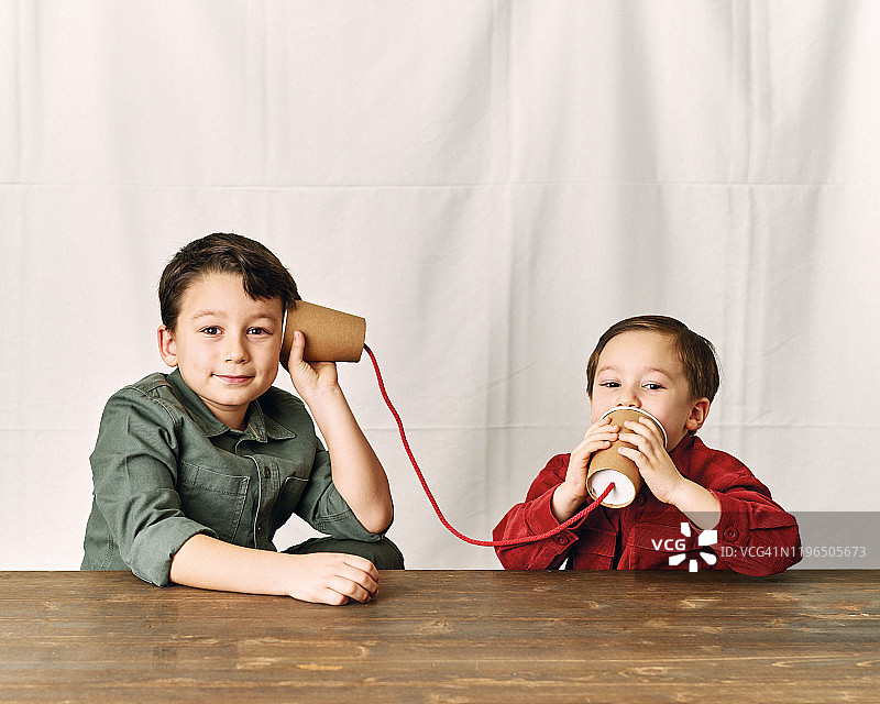 两个孩子正在用纸杯当电话。图片素材