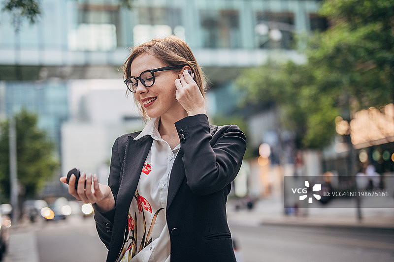 美丽的现代女士，带着无线耳机在市中心图片素材