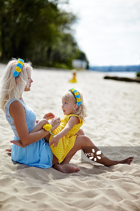 幸福的家庭在海边放松。快乐的家庭在夏天的海滩休息。年轻的母亲和她可爱的小女儿在海滩度假。夏季、童年和休闲的概念图片素材
