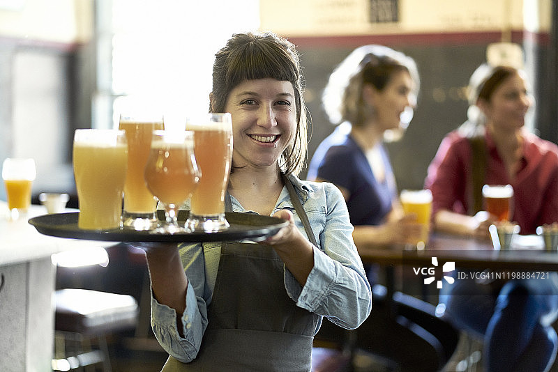 微笑的女服务员给顾客送啤酒图片素材