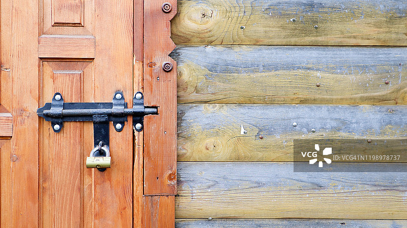 带有黑色金属插销的旧木门。近距离观察一个锁和闩在一个木门上。粗糙的木制金属门闩。这种滑动锁可以用在遮阳篷、桌面或栅栏上图片素材