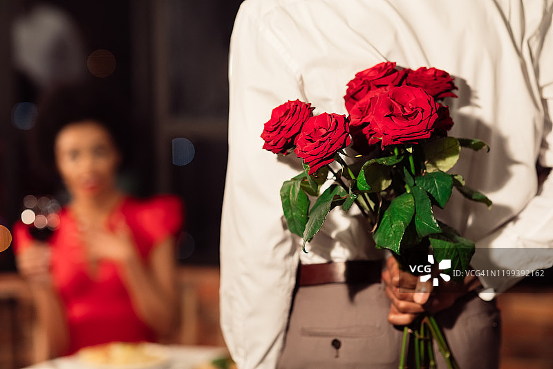 男友手捧一束玫瑰在餐厅祝贺女友图片素材