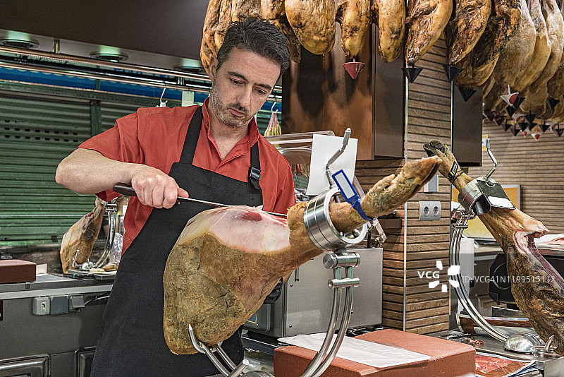 西班牙火腿屠夫正在切西班牙塞拉诺火腿片。图片素材