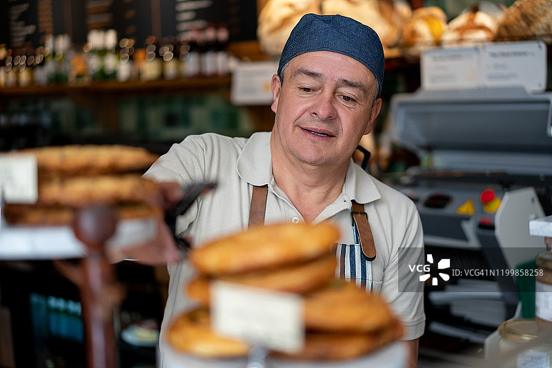 快乐的面包师在面包店卖糕点图片素材