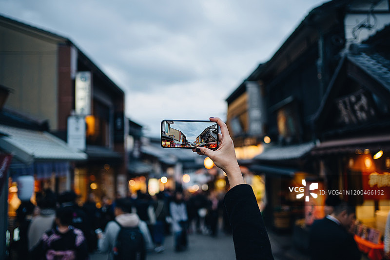 亚洲女游客在日本京都游览传统日本城镇时，用智能手机拍摄东山区的街景图片素材