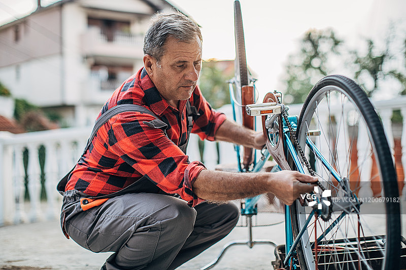 老人独自在前院修自行车图片素材