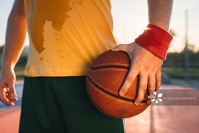 抱着篮球的汗流浃背的篮球运动员图片素材