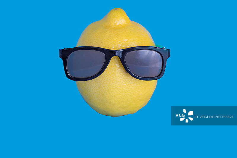 一个有趣的热带柠檬在蓝色背景与太阳镜图片素材