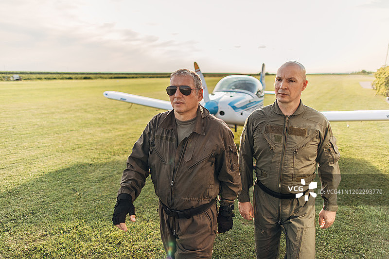 两个成熟的飞行员站在螺旋桨飞机旁边图片素材