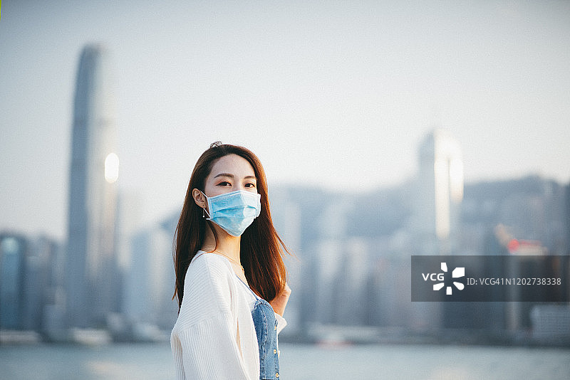 一名年轻的亚洲女子戴着防护口罩，以防止冠状病毒的传播，这是一场全球卫生紧急事件的爆发图片素材