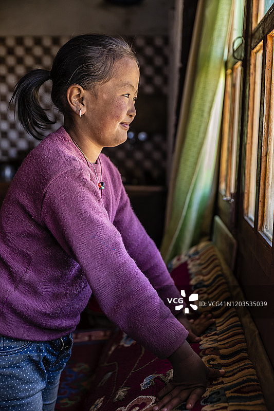 西藏小女孩透过窗户往外看，上野马，尼泊尔图片素材