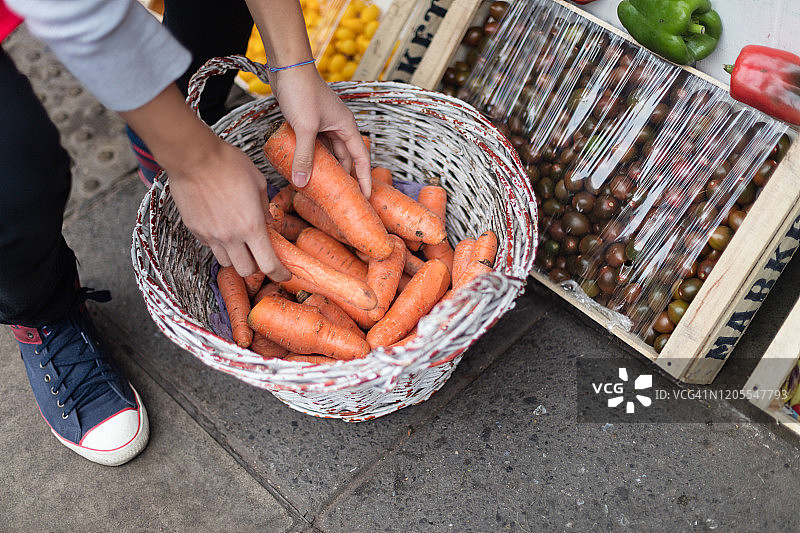 蔬菜水果店的售货员，手里拿着满满一篮子胡萝卜图片素材