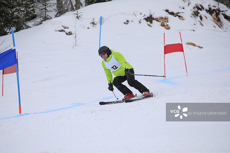 业余冬季运动高山滑雪大回转比赛。老年男子在滑雪场滑雪。高山雪景图片素材