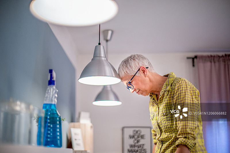 一位老妇人在擦拭一盏满是灰尘的灯。图片素材