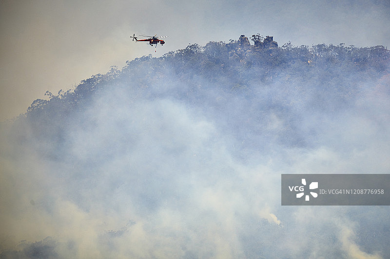 澳大利亚，森林大火和消防直升机在烟雾弥漫的山谷中图片素材