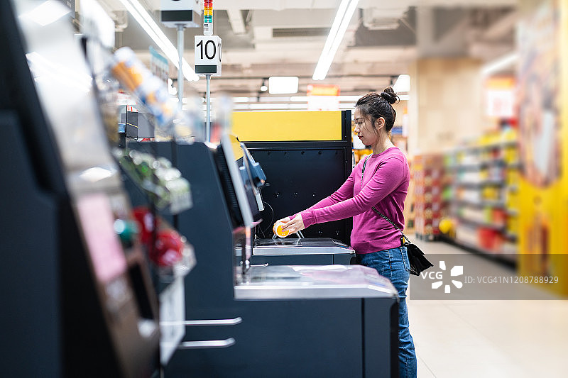 亚洲女性在超市用自动付款机结账图片素材
