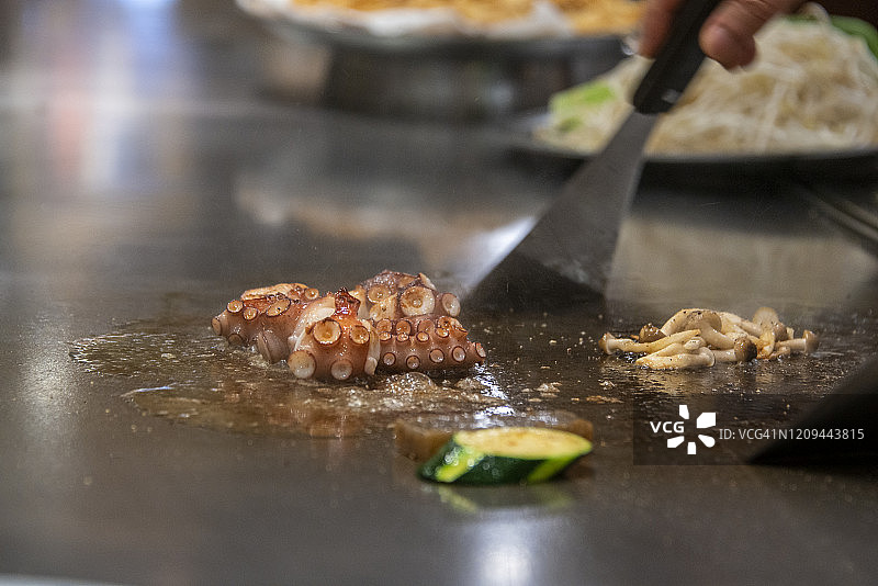 在日本神户，一名日本厨师在烤盘上煮小章鱼图片素材