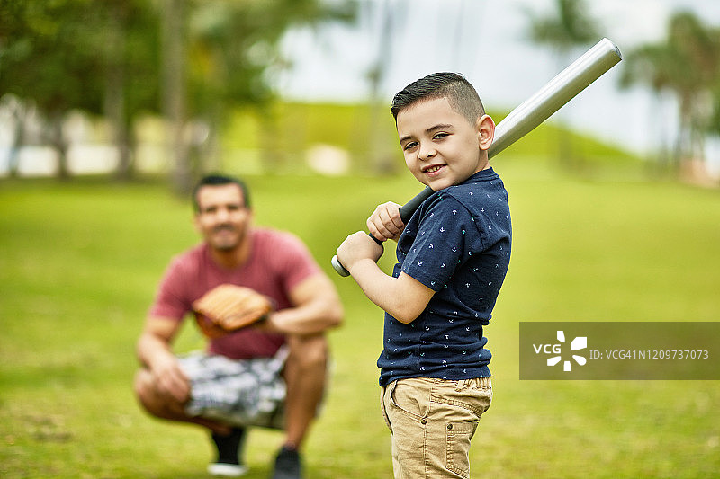 自信的西班牙男孩拿着棒球棒在迈阿密公园图片素材