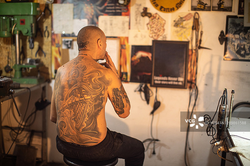 纹身艺术家与纹身头坐在他的工作室，看他的艺术作品图片素材