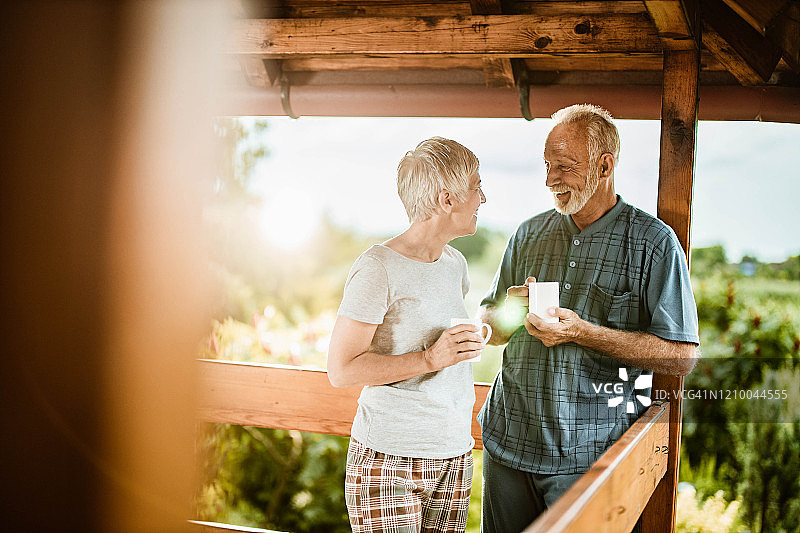 一对快乐的老年夫妇在露台上喝咖啡聊天。图片素材