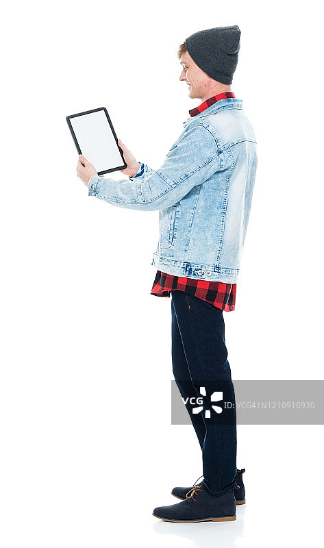 白人潮男穿着牛仔裤站在白色背景前使用触摸屏图片素材