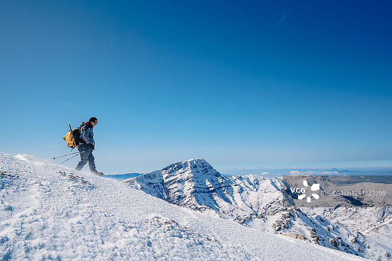 老年登山是冬季在高海拔山脉的顶峰行走图片素材