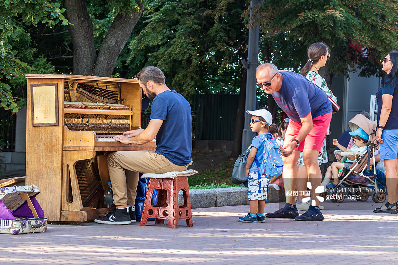 不明身份的音乐家在基辅中心的米哈伊洛夫斯卡娅广场上弹奏钢琴。街头文化。图片素材