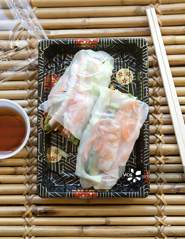 外卖用筷子夹在托盘里的春卷和蘸酱放在竹桌上——这是一系列的一部分图片素材