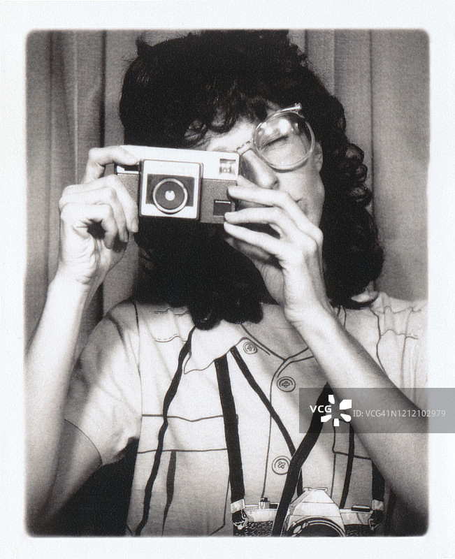 复古风格的20世纪80年代的女人用复古相机拍照图片素材