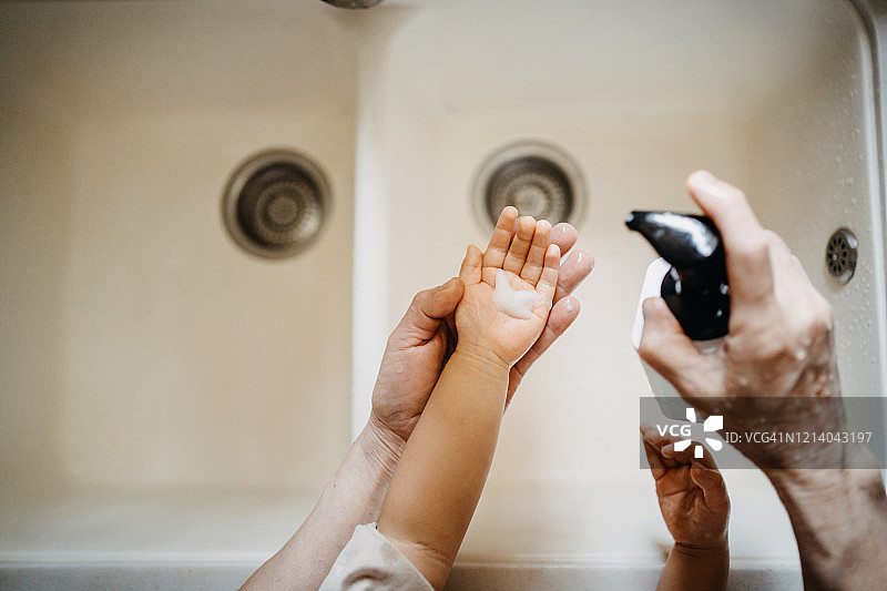 头顶的视图，一个祖母用肥皂给小孙女的手和洗他们的手一起在水槽图片素材
