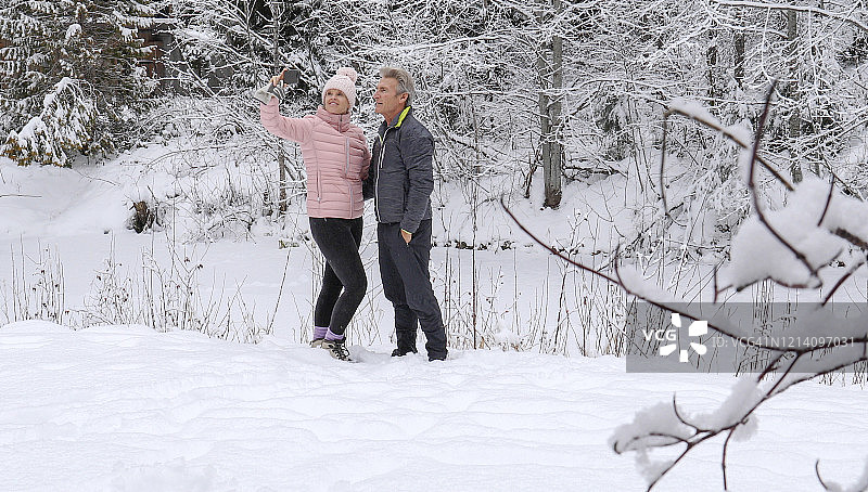 一对成熟的夫妇在白雪覆盖的河岸放松图片素材