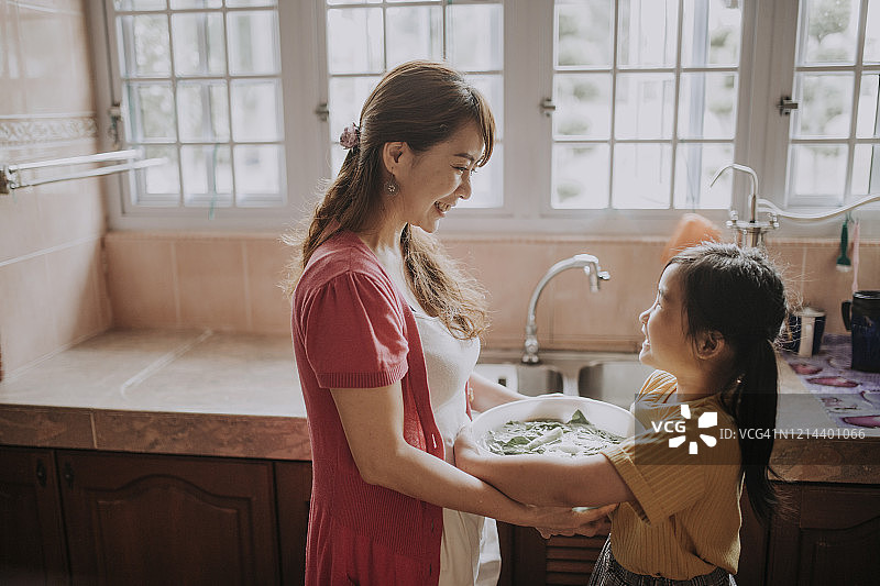 一位亚裔中国家庭主妇和她的女儿在厨房准备食物图片素材