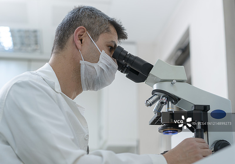 男科学家坐在现代实验室里看显微镜图片素材