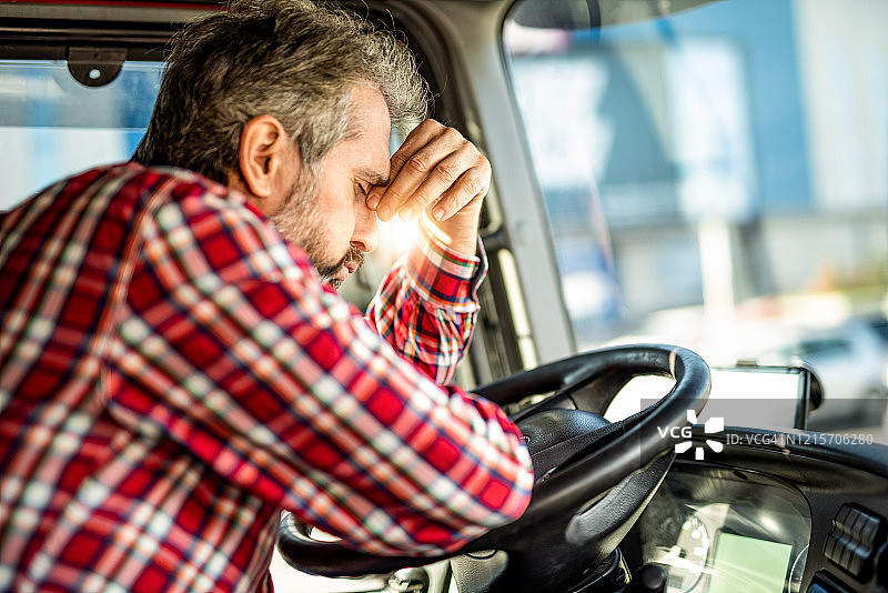 疲惫成熟的卡车司机在车流中等待，思考着工作上的问题。图片素材