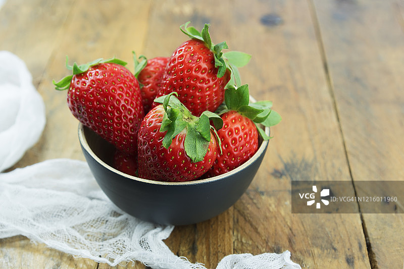 新鲜的有机成熟草莓在一个碗在乡村木制背景和复制空间。图片素材