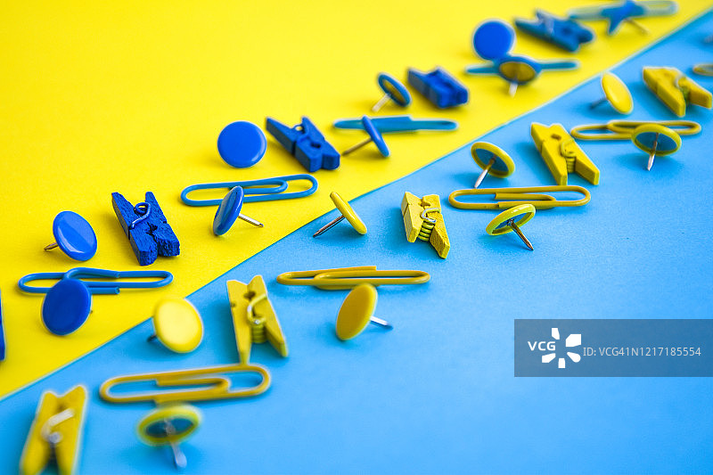 办公用品以彩色纽扣和回形针的形式出现，衣服别针以黄色和蓝色为背景，复制空间图片素材