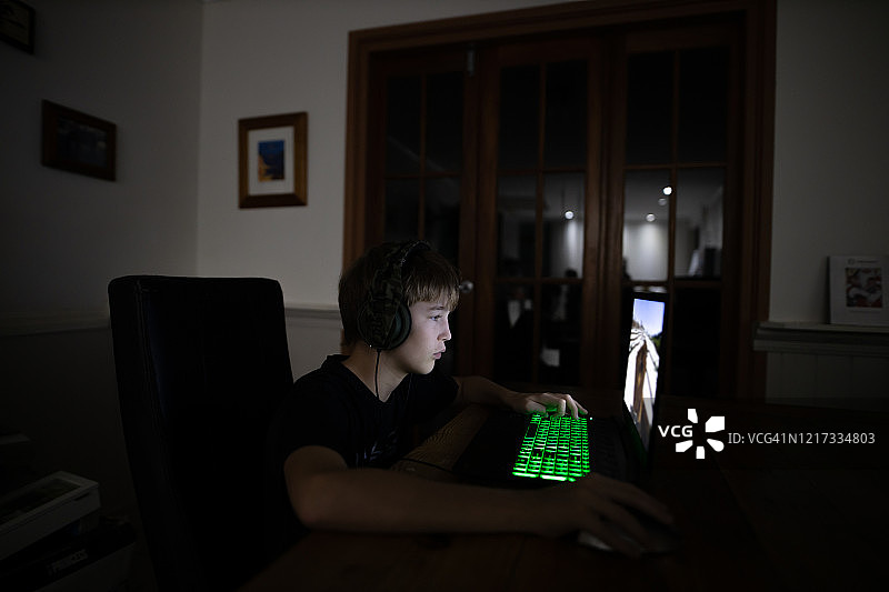 男孩在黑暗中玩电脑游戏图片素材