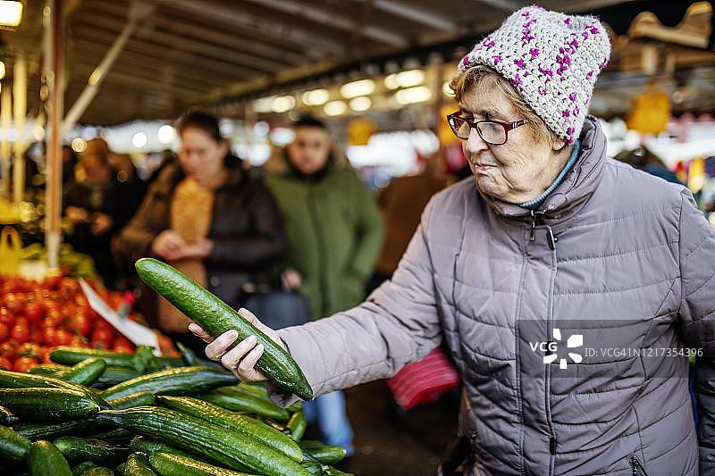 德国北莱茵-威斯特法伦州科隆市，一名老人在每周一次的市场上检查黄瓜图片素材