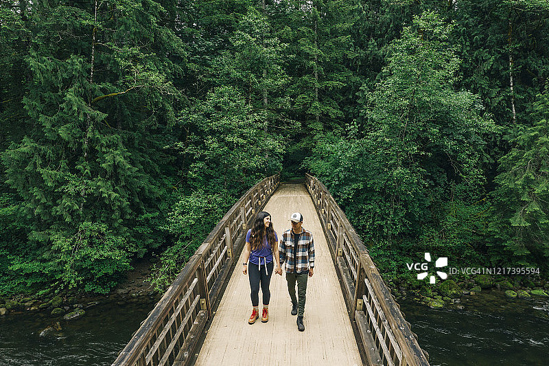 一对年轻夫妇喜欢在太平洋西北部的一座桥上徒步旅行。图片素材