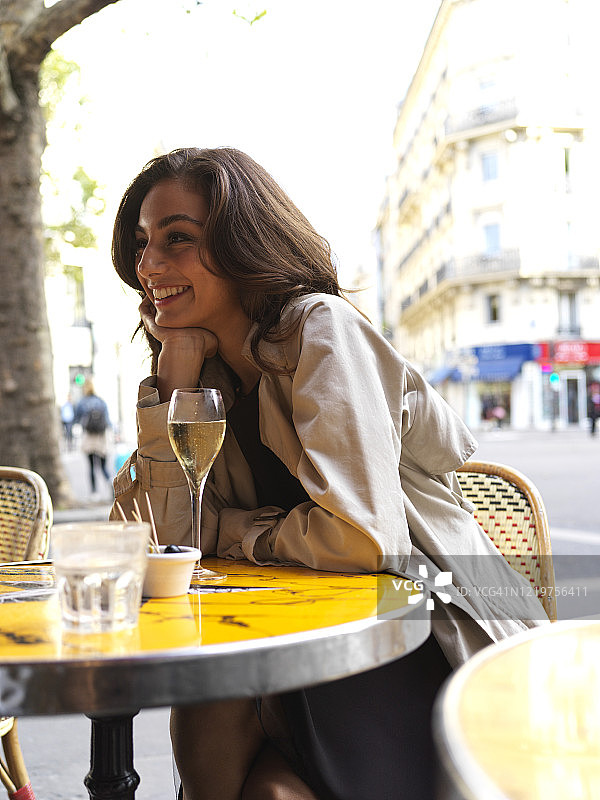 时髦的年轻女性坐在咖啡厅露台在法国巴黎，白天图片素材