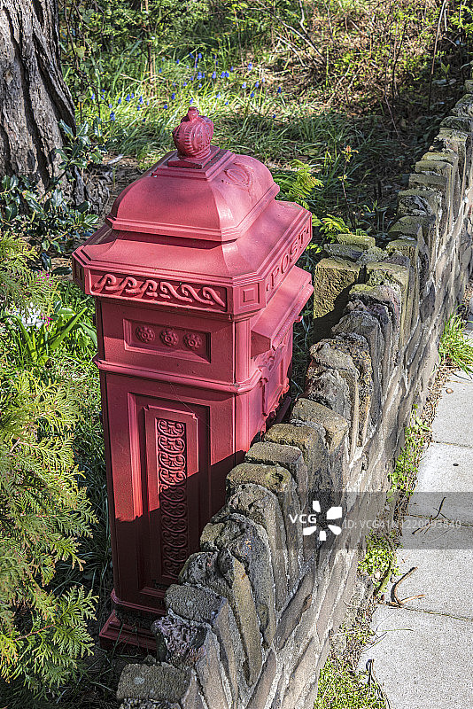一个红色的老式荷兰邮箱放在外面的花园里图片素材
