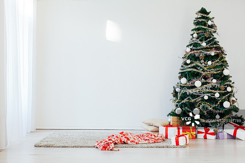 圣诞树上挂着新年礼物的白色房间内部图片素材