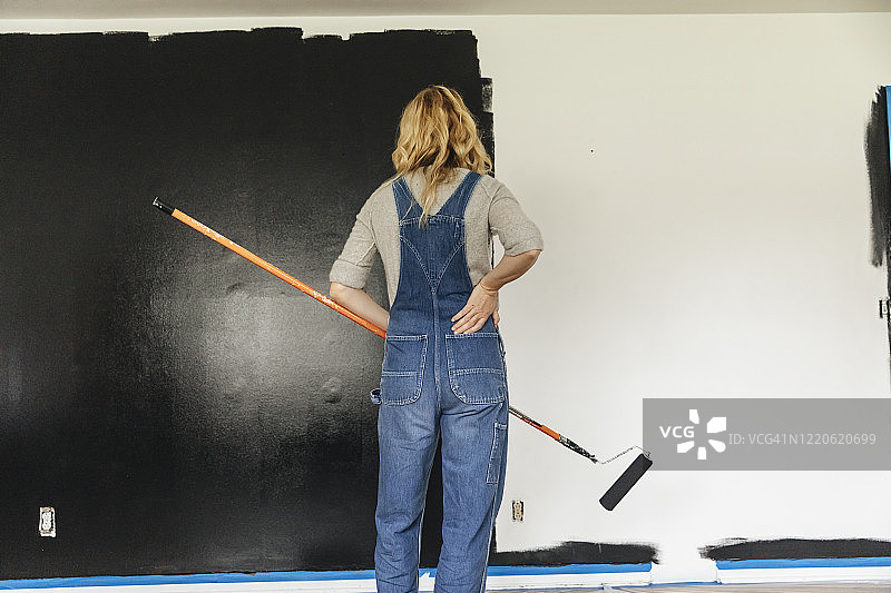 女人站在家里看着粉刷的墙图片素材